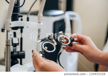 Close up view of female doctor's hands that are holding ophthalmologist glasses Close up view of female doctor's hands that are holding ophthalmologist glasses 134455526