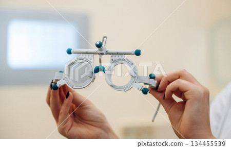 Close up view of female doctor's hands that are holding ophthalmologist glasses Close up view of female doctor's hands that are holding ophthalmologist glasses 134455539
