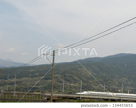 新幹線列車行駛在遠處山脈的映襯下。 新幹線列車行駛在遠處山脈的映襯下。 134455653