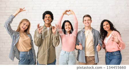 Love, friendship, youth, lifestyle. Teen happy multiracial friends gesturing with hands, people team in casual have fun and looking at camera, on white brick wall background, panorama, copy space Love, friendship, youth, lifestyle. Teen happy multiracial friends gesturing with hands, people team in casual have fun and looking at camera, on white brick wall background, panorama, copy space 134455660