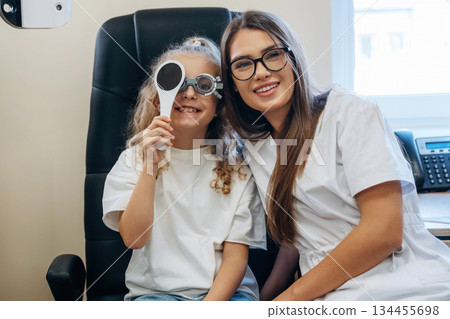 Helping, covering the eye. Little girl at the ophthalmologist clinic with doctor 134455698