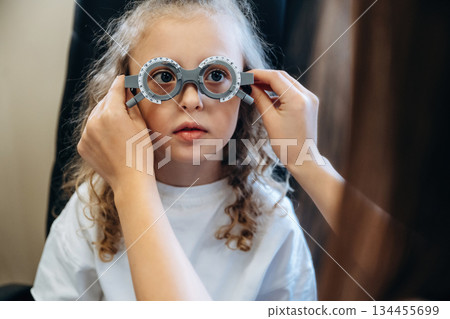 Standing, wearing the special glasses. Little girl at the ophthalmologist clinic with doctor 134455699