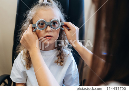 Standing, wearing the special glasses. Little girl at the ophthalmologist clinic with doctor 134455700
