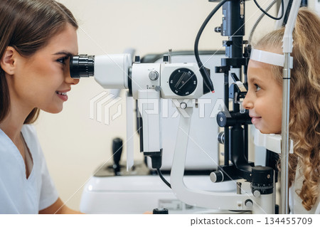 View from the side. Little girl at the ophthalmologist clinic with doctor 134455709