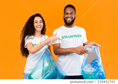 Don't Litter. Male And Female Multicultural Volunteers Picking Wasted Plastic Cleaning And Sorting Trash Holding Blue Garbage Bags Posing Over Yellow Studio Background. Ecology, Keep Environment Clean 134455741