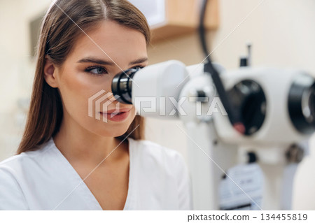 Digital optical device. Young female ophthalmologist is in the cabinet Digital optical device. Young female ophthalmologist is in the cabinet 134455819