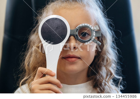 Healthcare conception, sitting, looking. Little girl is checking vision in the ophthalmologist cabinet 134455986