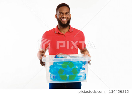 Black Guy Holding Box With Recycle Symbol Full Of Used Plastic Bottles Sorting His Waste For Disposal Standing On White Studio Background, Smiling To Camera. Junk Sorting And Recycling Concept Black Guy Holding Box With Recycle Symbol Full Of Used Plastic Bottles Sorting His Waste For Disposal Standing On White Studio Background, Smiling To Camera. Junk Sorting And Recycling Concept 134456215