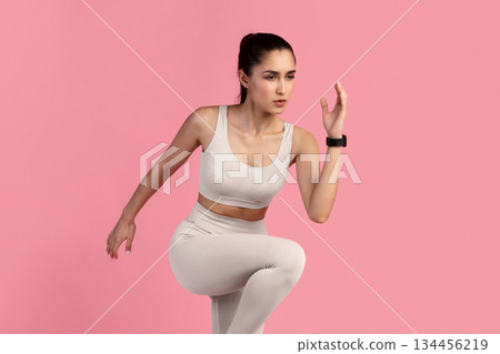 Sport Exercises And Healthy Lifestyle. Full Length Portrait Of Determined Slim Young Lady Running And Sprinting, Wearing Fitness Bracelet, Lifting Leg Up, Exercising Isolated On Pink Studio Background Sport Exercises And Healthy Lifestyle. Full Length Portrait Of Determined Slim Young Lady Running And Sprinting, Wearing Fitness Bracelet, Lifting Leg Up, Exercising Isolated On Pink Studio Background 134456219