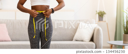 Weight Gain. Shocked Black Woman Weighing Herself And Measuring Her Waist Standing On Scales Unhappy With Result At Home. Slimming And Weight-Loss Failure Concept. Full Length 134456230