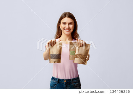 Eco Food Storing. Positive Young Lady Holding Three Kraft Paper Doypack Bags With Weight Groceries, Smiling Millennial Woman Choosing Biodegradable Ziplock Packs, Posing Over Light Grey Background Eco Food Storing. Positive Young Lady Holding Three Kraft Paper Doypack Bags With Weight Groceries, Smiling Millennial Woman Choosing Biodegradable Ziplock Packs, Posing Over Light Grey Background 134456236