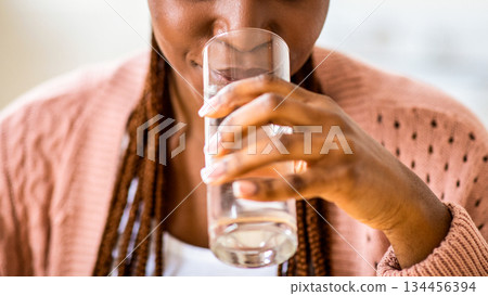 Refreshing Drink. Beautiful Young Black Lady Drinking Water From Glass At Home, Enjoying Clean Mineral Liquid While Relaxing In Kitchen, Taking Healthy Beverage For Body Hydration, Closeup, Cropped Refreshing Drink. Beautiful Young Black Lady Drinking Water From Glass At Home, Enjoying Clean Mineral Liquid While Relaxing In Kitchen, Taking Healthy Beverage For Body Hydration, Closeup, Cropped 134456394