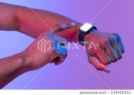 Unrecognizable african american male using smartwatch with blank screen, checking digital data, black guy standing in neon light over purple studio background, cropped image with copy space, mockup Unrecognizable african american male using smartwatch with blank screen, checking digital data, black guy standing in neon light over purple studio background, cropped image with copy space, mockup 134456431