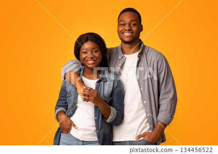 Portrait of joyful smiling black couple embracing and smiling at camera, handsome young african american boyfriend and girlfriend standing together isolated over yellow background, copy space Portrait of joyful smiling black couple embracing and smiling at camera, handsome young african american boyfriend and girlfriend standing together isolated over yellow background, copy space 134456522
