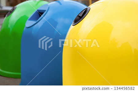 Waste Sorting Concept. Closeup Shot Of Colorful Garbage Containers For Different Sort Of Materials Standing Outdoors, Yellow Blue And Green Trash Bin For Diverse Kind Of Trash For Recycling Waste Sorting Concept. Closeup Shot Of Colorful Garbage Containers For Different Sort Of Materials Standing Outdoors, Yellow Blue And Green Trash Bin For Diverse Kind Of Trash For Recycling 134456582