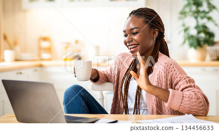 Online Communication. Cheerful Black Female Freelancer Talking At Laptop Camera And Drinking Coffee, Relaxing In Kitchen At Home, Smiling African American Lady Enjoying Pleasant Conversation Online Communication. Cheerful Black Female Freelancer Talking At Laptop Camera And Drinking Coffee, Relaxing In Kitchen At Home, Smiling African American Lady Enjoying Pleasant Conversation 134456633