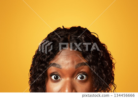 Closeup of millennial black woman surprised eyes, orange studio, background. Amazed african american young lady staring at camera. Emotions and looks, human eyes, face expressions concept 134456666
