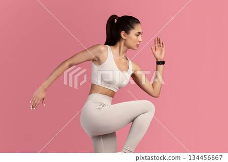 Fitness And Sport Concept. Full Length Portrait Of Confident Fit Young Woman Wearing Activity Tracker Running, Lifting Leg Up, Exercising Isolated On Pink Background, Studio Shot. Energy And Workout 134456867