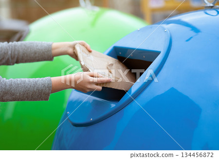 Paperwaste Sorting. Unrecognizable woman throwing carton package into blue garbage recycle bin outdoors, eco-friendly lady caring about environment, cropped image with selective focus 134456872