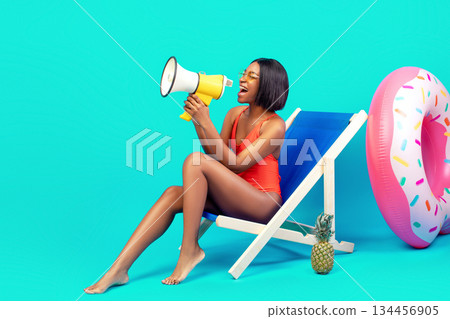 Amazing offer. Young black woman in swimsuit sitting in lounge chair, shouting into megaphone, making announcement, sharing great news on blue studio background, banner design with free space Amazing offer. Young black woman in swimsuit sitting in lounge chair, shouting into megaphone, making announcement, sharing great news on blue studio background, banner design with free space 134456905