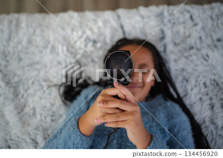 Young girl smiling holding vintage camera filming overhead Young girl smiling holding vintage camera filming overhead 134456920