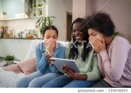 Family enjoying online shopping at home, laughing and bonding 134456935