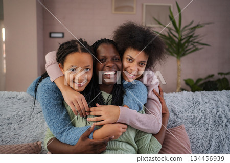 Happy Black mother embracing her two daughters smiling 134456939