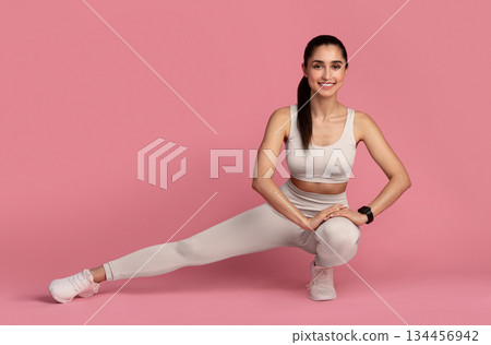 Leg And Glute Training. Smiling Fit Young Lady In Sportswear Doing Deep Side Squat Exercise During Workout, Warming Up, Isolated On Pink Studio Background. Full Length, Copy Space. Fitness And Sport. 134456942