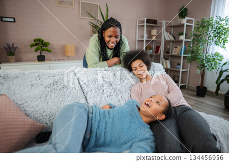 African American mother and daughters relaxing and laughing at home 134456956
