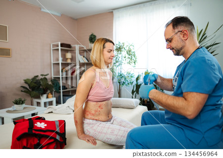 Doctor examining female patient with rash at home 134456964