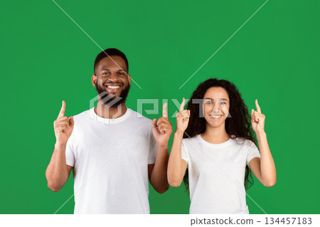 Diverse Couple Pointing Fingers Up Posing Standing In Studio Over Green Background, Smiling To Camera. Multiethnic Man And Woman Showing Something Above Their Heads. Look Upward, Advertisement Banner Diverse Couple Pointing Fingers Up Posing Standing In Studio Over Green Background, Smiling To Camera. Multiethnic Man And Woman Showing Something Above Their Heads. Look Upward, Advertisement Banner 134457183