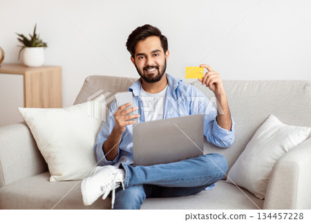 Handsome Arab Man Using Smartphone, Credit Card And Laptop Computer At Home, Making Online Payments, Handsome Eastern Guy Using Mobile App For Money Trasfers Or Shopping, Looking At Camera, Free Space Handsome Arab Man Using Smartphone, Credit Card And Laptop Computer At Home, Making Online Payments, Handsome Eastern Guy Using Mobile App For Money Trasfers Or Shopping, Looking At Camera, Free Space 134457228
