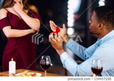 Marry Me. Black Man Making Marriage Proposal To His Girlfriend During Romantic Dinner In Restaurant, Giving Box With Diamond Ring, Doubtful Woman Thinking About Answer, Cropped Image, Selective Focus Marry Me. Black Man Making Marriage Proposal To His Girlfriend During Romantic Dinner In Restaurant, Giving Box With Diamond Ring, Doubtful Woman Thinking About Answer, Cropped Image, Selective Focus 134457280