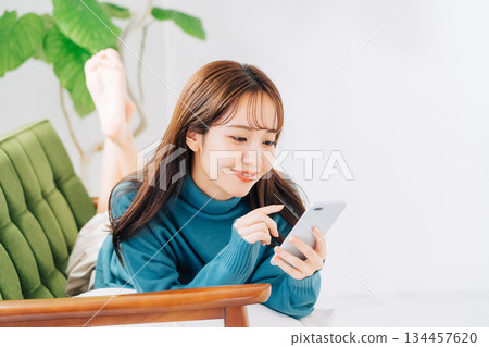 躺在沙發上使用智能手機的女人 134457620