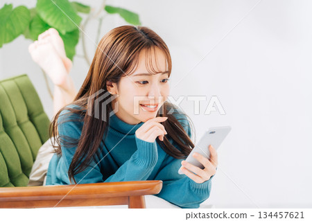 A woman lying on the sofa and using a smartphone 134457621