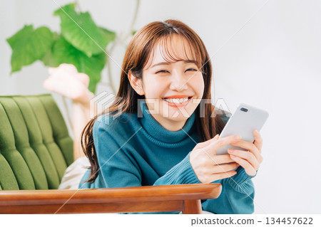 躺在沙發上使用智能手機的女人 134457622