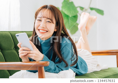 躺在沙發上使用智能手機的女人 134457631