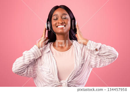 Relaxed black woman in headphones enjoying good song and smiling with closed eyes on pink studio background. Millennial African American lady listening to beautiful music, feeling happy and joyful Relaxed black woman in headphones enjoying good song and smiling with closed eyes on pink studio background. Millennial African American lady listening to beautiful music, feeling happy and joyful 134457958