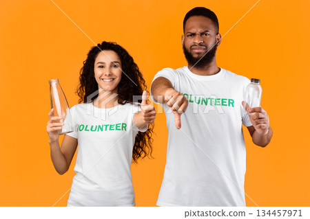 Don't Use Plastic. Two Mixed Volunteers Holding Glass And Plastic Bottles Gesturing Like And Dislike Disapproving Usage Of Single-Used Bottle Standing Over Yellow Studio Background 134457971