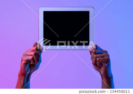 Hands Of African American Man Holding Digital Tablet With Black Blank Screen, Showing Free Copy Space For Your App Or Website Design, Standing In Neon Lighting Over Purple Studio Background, Mockup 134458011