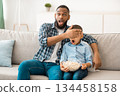 Questionable TV Content. Shocked Black Father Covering Son's Eyes Watching Television Together Sitting On Sofa At Home. Children Tv Programming Issues, Parental Control Concept 134458158
