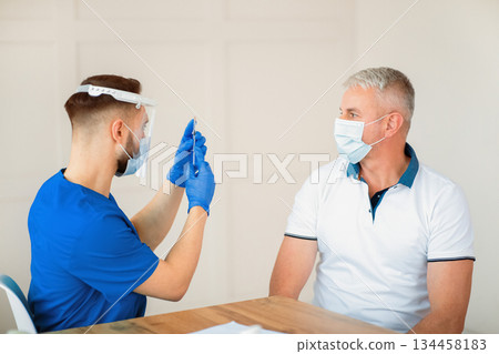 Immunization for older people. Serior man on visit to doctor, getting ready for coronavirus vaccine injection at clinic. Mature male patient being immunized against covid-19. Medical concept 134458183