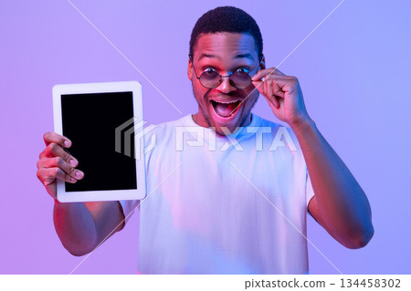 Check This App. Surprised African Guy In Sunglasses Holding Digital Tablet With Black Blank Screen For Mockup, Demonstrating Copy Space For Your Design, Standing In Neon Light On Purple Background Check This App. Surprised African Guy In Sunglasses Holding Digital Tablet With Black Blank Screen For Mockup, Demonstrating Copy Space For Your Design, Standing In Neon Light On Purple Background 134458302