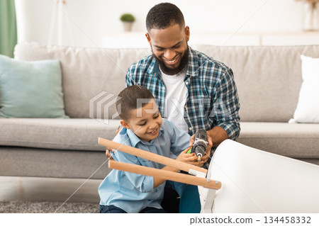 Happy Black Father And Son Fixing Table Working Doing House Chores Together At Home. Household Chores For Kid, Child Care And Housework Concept. Selective Focus 134458332