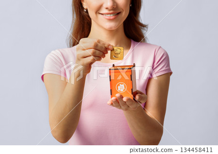 Metal Waste Recycling. Unrecognizable Lady Inserting Card With Aluminium Can Icon Into Wooden Toy Trash Container, Standing Over Light Studio Background, Conceptual Image For Garbage Sorting, Closeup Metal Waste Recycling. Unrecognizable Lady Inserting Card With Aluminium Can Icon Into Wooden Toy Trash Container, Standing Over Light Studio Background, Conceptual Image For Garbage Sorting, Closeup 134458411