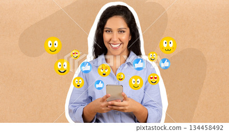 A lady smiles while holding a smartphone, engaging in chatting and messaging. Emojis surround her, reflecting joyful interactions and social media connections in a vibrant setting. A lady smiles while holding a smartphone, engaging in chatting and messaging. Emojis surround her, reflecting joyful interactions and social media connections in a vibrant setting. 134458492