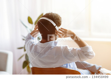 Unrecognizable Man Listening Music In Wireless Headphones At Home And Looking To Window, Brunette Guy Relaxing In Comfortable Chair And Enjoying His Favorite Melodies, Rear View With Copy Space Unrecognizable Man Listening Music In Wireless Headphones At Home And Looking To Window, Brunette Guy Relaxing In Comfortable Chair And Enjoying His Favorite Melodies, Rear View With Copy Space 134458499
