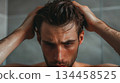 Young man washing his hair, water running down his face, in a steamy shower Young man washing his hair, water running down his face, in a steamy shower 134458525