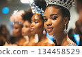 A woman adorned with a bejeweled crown stands out during a beauty pageant, with fellow contestants blurred in the background. A woman adorned with a bejeweled crown stands out during a beauty pageant, with fellow contestants blurred in the background. 134458529