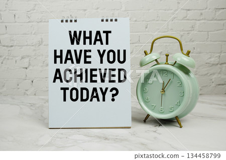 What Have You Achieved Today? with green vintage alarm clock against a white brick wall background. 134458799
